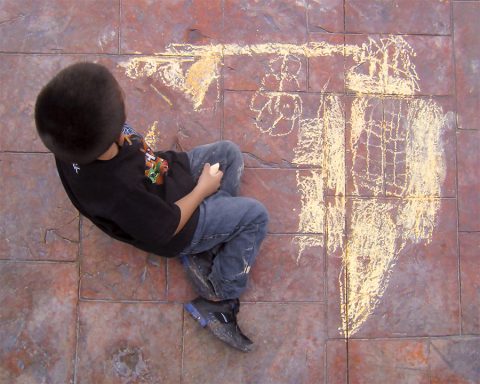 Chalk Drawing. A boy creating a challenge drawing on a concrete walkway.